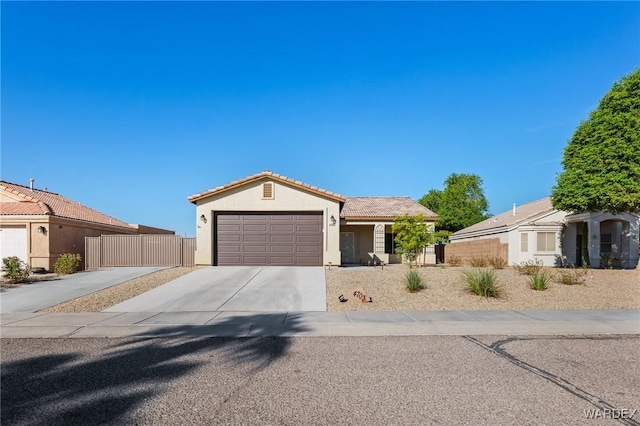 view of front of house with driveway, a tiled roof, an attached garage, fence, and stucco siding