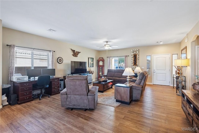 living room with a ceiling fan, light wood-type flooring, and visible vents