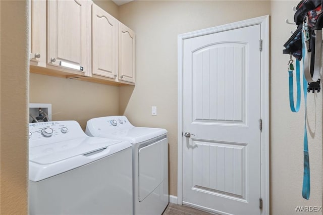 clothes washing area featuring cabinet space and separate washer and dryer