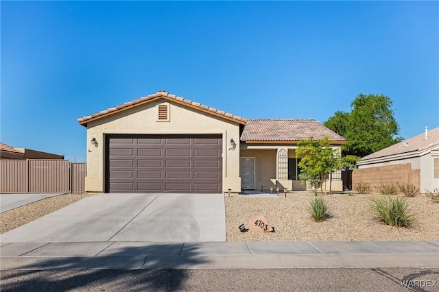 view of front of property with a tile roof, stucco siding, concrete driveway, fence, and a garage