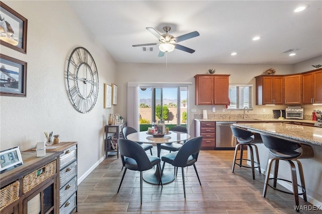 kitchen featuring light stone countertops, plenty of natural light, dark wood-style flooring, and stainless steel dishwasher