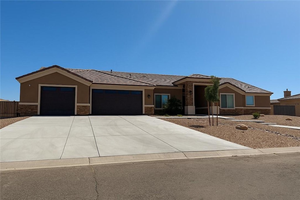 4238 Gemstone Ave, Kingman, AZ 86401 - view of front of house with an attached garage, stone siding, concrete driveway, stucco siding, and a tile roof