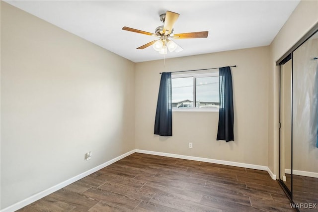 unfurnished bedroom with dark wood-style floors, a closet, a ceiling fan, and baseboards