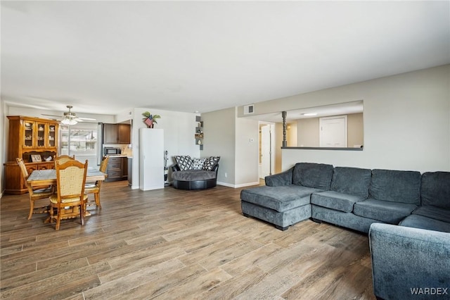 living area featuring visible vents, baseboards, ceiling fan, and wood finished floors