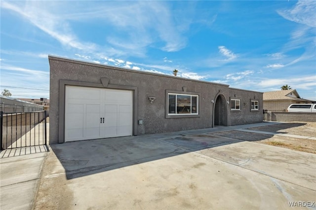 view of front of property featuring a garage, driveway, fence, and stucco siding