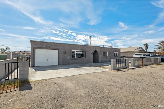 view of front of home with a fenced front yard, a garage, concrete driveway, a gate, and stucco siding