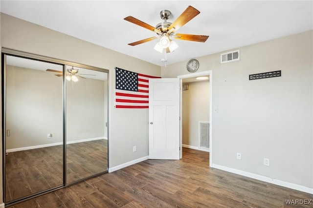 unfurnished bedroom featuring baseboards, visible vents, dark wood finished floors, and a closet