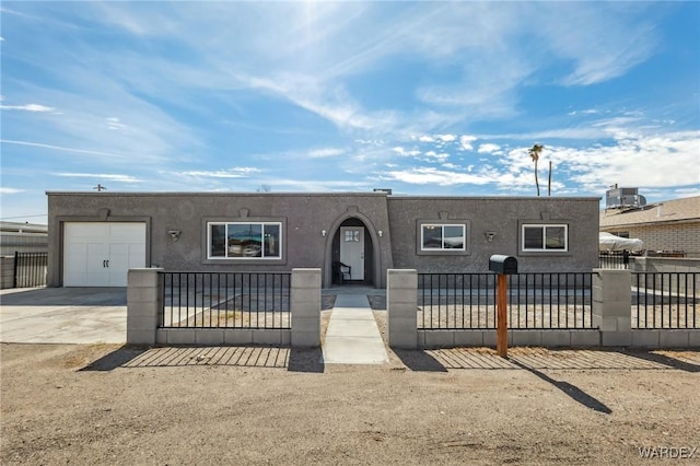 view of front of property featuring a garage, concrete driveway, a fenced front yard, and stucco siding