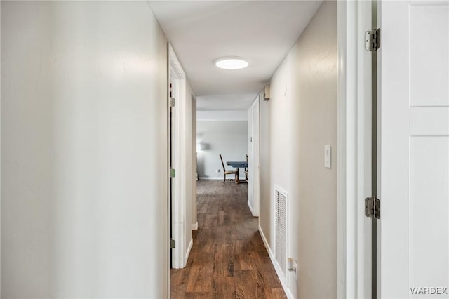 hallway with baseboards, visible vents, and dark wood-type flooring