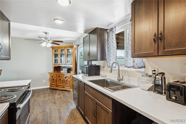 kitchen featuring light countertops, electric range, a sink, wood finished floors, and black microwave