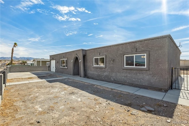 view of front of property with fence, a patio, and stucco siding