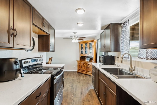 kitchen with light wood-style flooring, electric range, a sink, baseboards, and light countertops