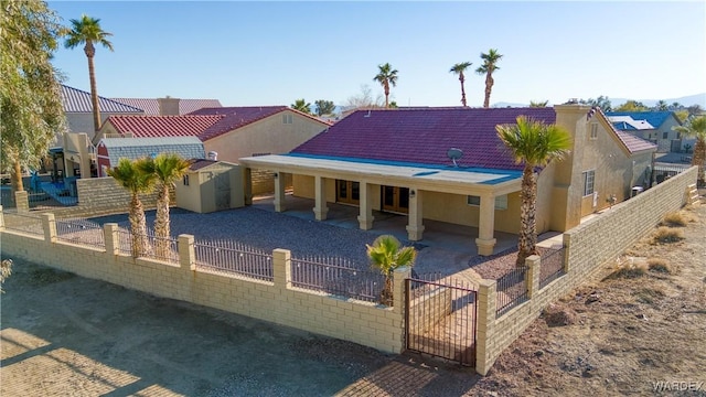 rear view of property with fence private yard, stucco siding, an outbuilding, and a storage unit