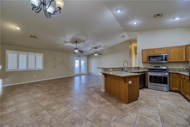 kitchen with visible vents, appliances with stainless steel finishes, brown cabinetry, open floor plan, and a sink