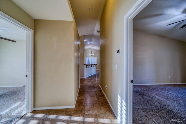 hallway with a chandelier, carpet flooring, and baseboards