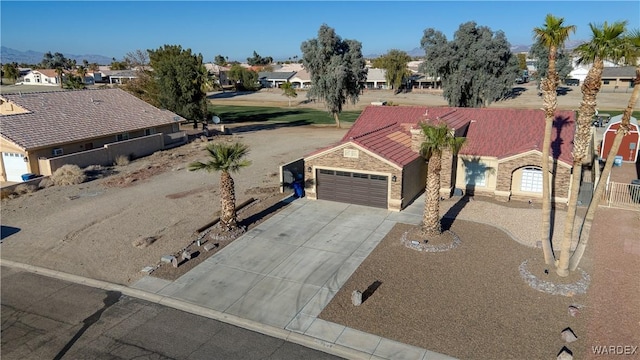 view of front of property with an attached garage, a tile roof, driveway, stone siding, and a residential view