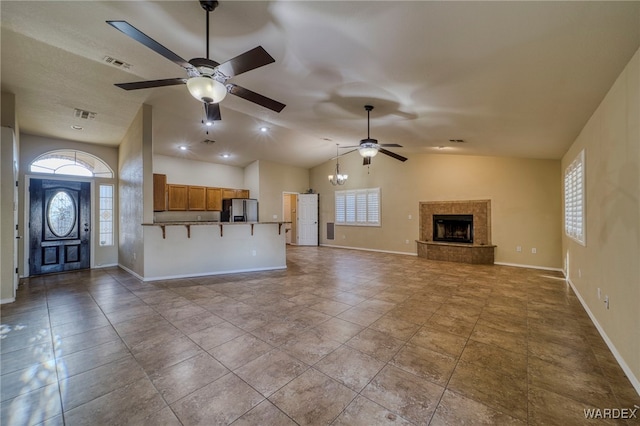 unfurnished living room with visible vents, baseboards, a tile fireplace, lofted ceiling, and ceiling fan