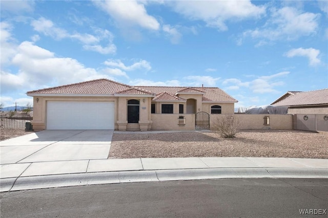 mediterranean / spanish house featuring a fenced front yard, a garage, a tile roof, concrete driveway, and a gate