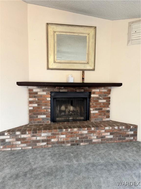 interior details featuring a textured ceiling, carpet floors, and a fireplace