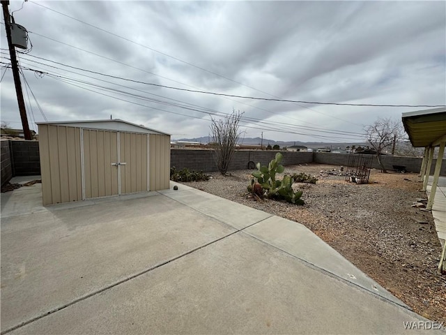 exterior space with a storage shed, a fenced backyard, a patio area, and an outbuilding