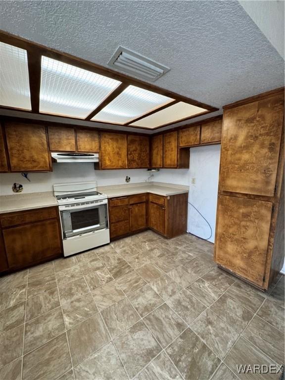 kitchen featuring light countertops, visible vents, electric range, brown cabinetry, and ventilation hood