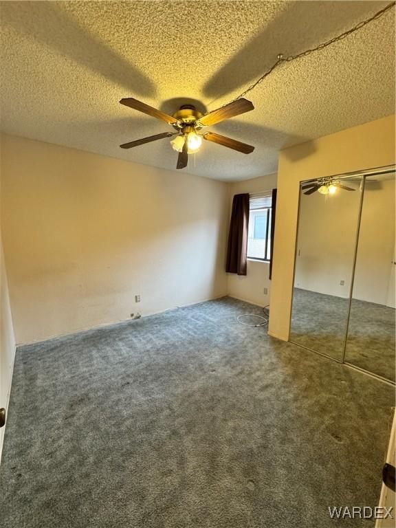 unfurnished bedroom with a ceiling fan, a closet, carpet flooring, and a textured ceiling