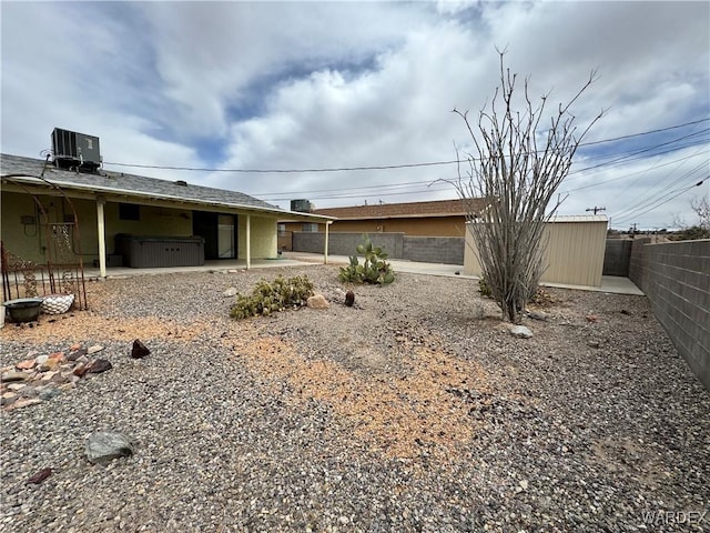 view of front of home with a hot tub, central AC unit, a fenced backyard, an outdoor structure, and a patio area