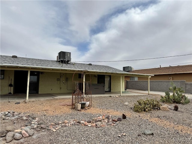 view of front of house with central AC, a patio area, fence, and stucco siding