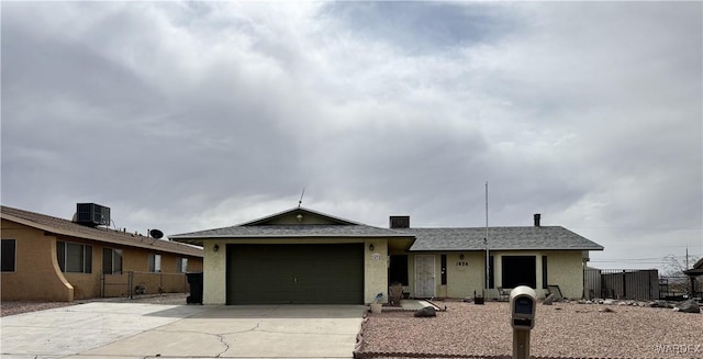 ranch-style house featuring a garage, concrete driveway, fence, and stucco siding