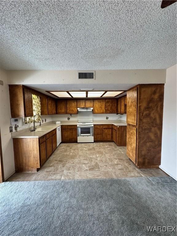 kitchen with visible vents, stainless steel range, dishwasher, brown cabinets, and light countertops