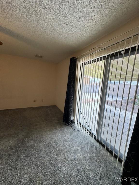 spare room featuring a textured ceiling, carpet flooring, and visible vents