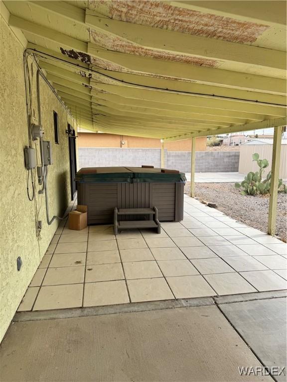 view of patio / terrace with fence and a hot tub