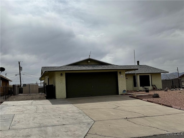 ranch-style house with an attached garage, fence, and stucco siding