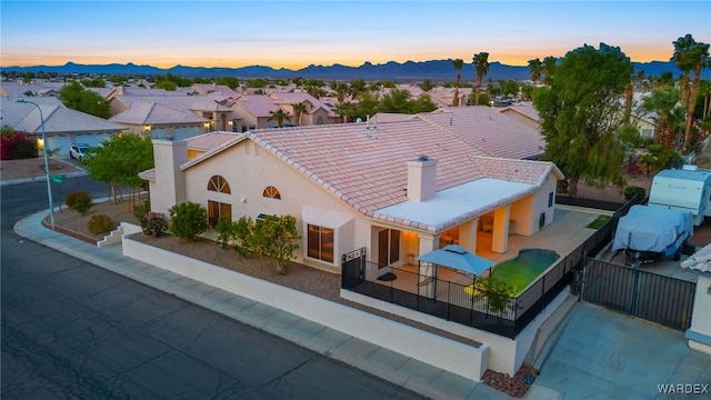1878 E Clear Lake Dr, Fort Mohave, AZ 86426 - exterior space featuring a chimney, fence, a tiled roof, stucco siding, and a mountain view