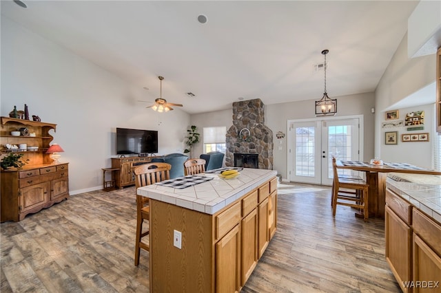 1878 E Clear Lake Dr, Fort Mohave, AZ 86426 - kitchen with tile counters, light wood-style floors, vaulted ceiling, and a fireplace