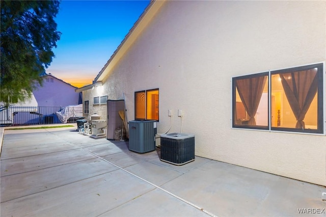 1878 E Clear Lake Dr, Fort Mohave, AZ 86426 - property exterior at dusk with central air condition unit, fence, a patio area, and stucco siding