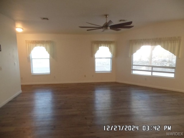 unfurnished room with ceiling fan, plenty of natural light, and dark wood finished floors