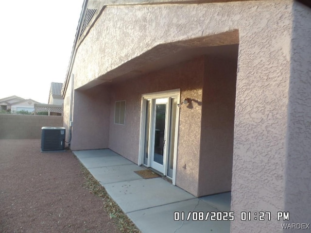 view of property exterior with central AC unit, a patio area, fence, and stucco siding