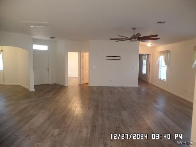 unfurnished living room with dark wood-style floors, visible vents, plenty of natural light, and a ceiling fan