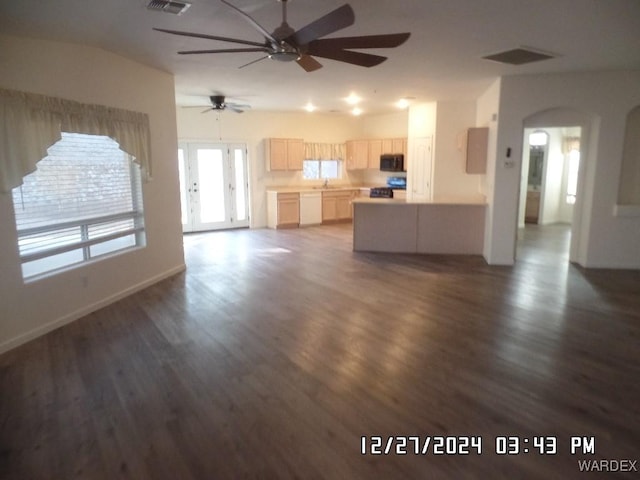 unfurnished living room featuring dark wood-style floors, arched walkways, visible vents, and a sink