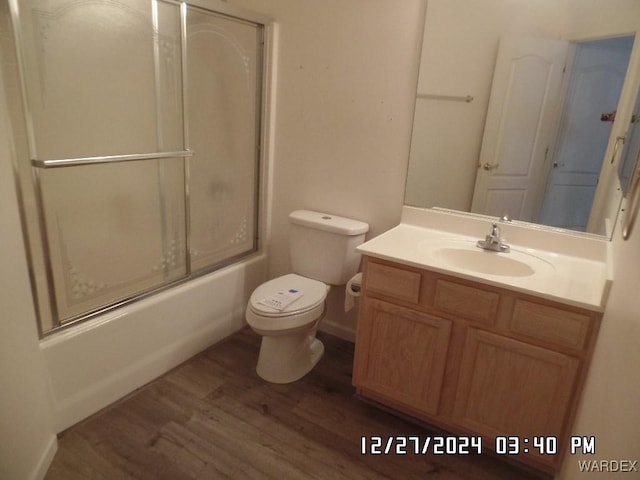 bathroom featuring combined bath / shower with glass door, vanity, toilet, and wood finished floors