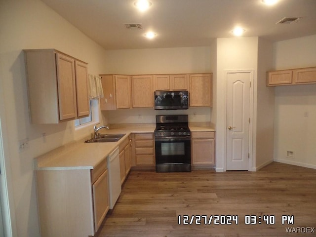 kitchen with light countertops, light brown cabinetry, gas stove, and a sink