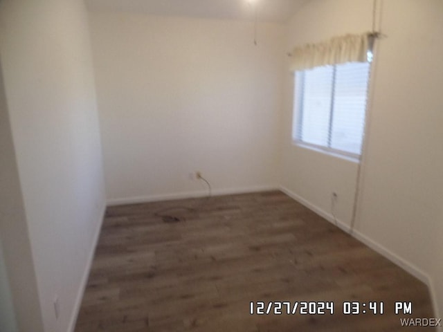 unfurnished room with dark wood-style flooring and baseboards