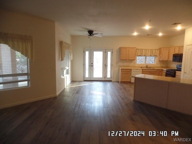 kitchen featuring light countertops, light brown cabinetry, a healthy amount of sunlight, black appliances, and a sink