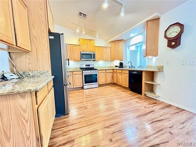 kitchen featuring vaulted ceiling, appliances with stainless steel finishes, light brown cabinets, and light stone counters