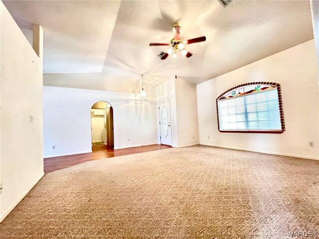 spare room featuring arched walkways, vaulted ceiling, ceiling fan, and baseboards