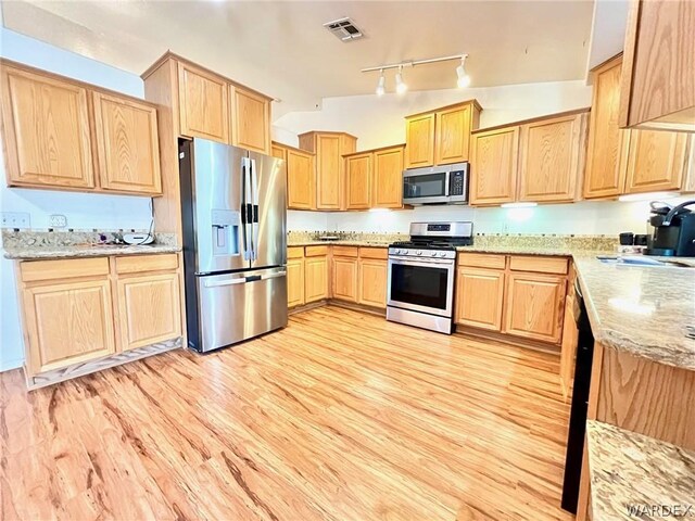 kitchen with light wood finished floors, visible vents, light stone counters, stainless steel appliances, and a sink