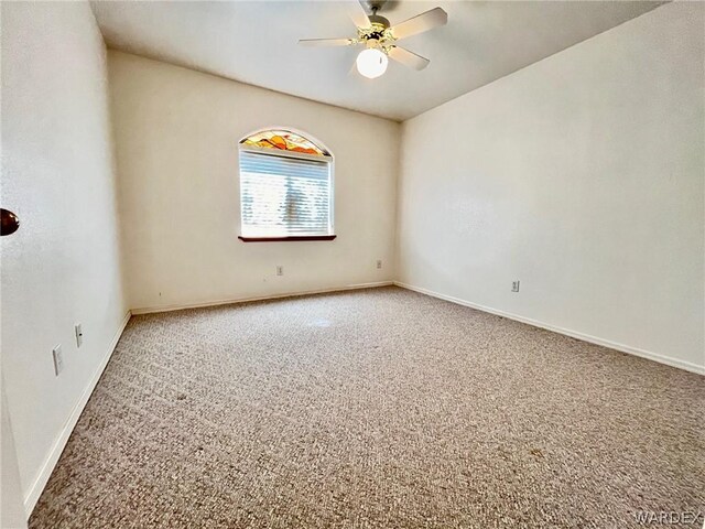 carpeted spare room with ceiling fan and baseboards