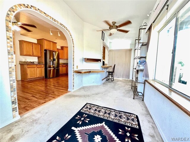 kitchen featuring arched walkways, stainless steel fridge, a ceiling fan, and a healthy amount of sunlight