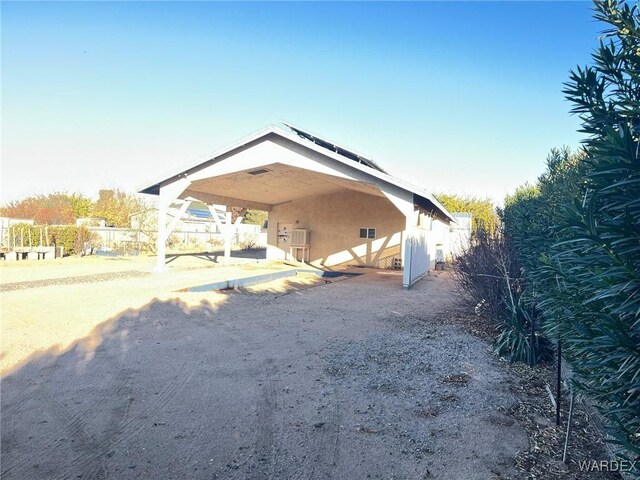 exterior space with fence, a carport, and stucco siding